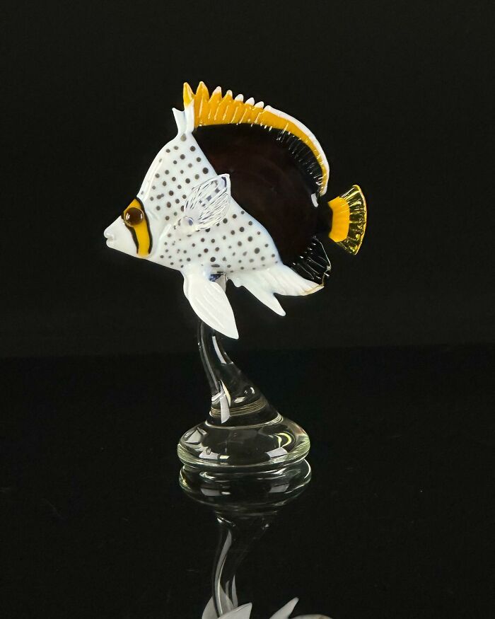 Glass sculpture of a colorful ocean fish with black, white, and yellow patterns on a clear glass base.