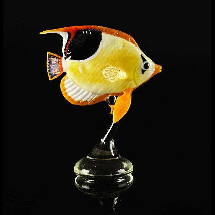 Glass sculpture of a colorful tropical fish showcasing stunning craftsmanship and ocean life artistry on a black background.