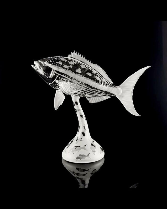 Glass sculpture of a detailed fish with ocean life patterns on a stand, representing stunning ocean-themed glass art.