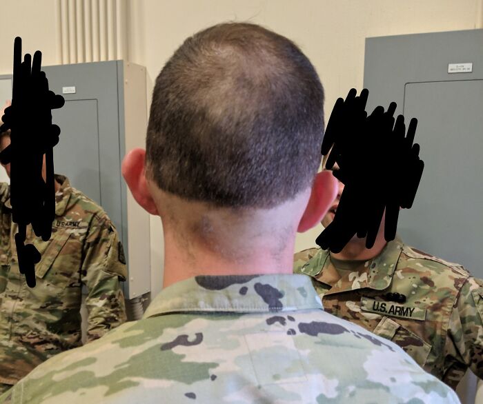 Close-up of a soldier with a tragic hair accident showing uneven haircut and patchy hair on the back of the head.