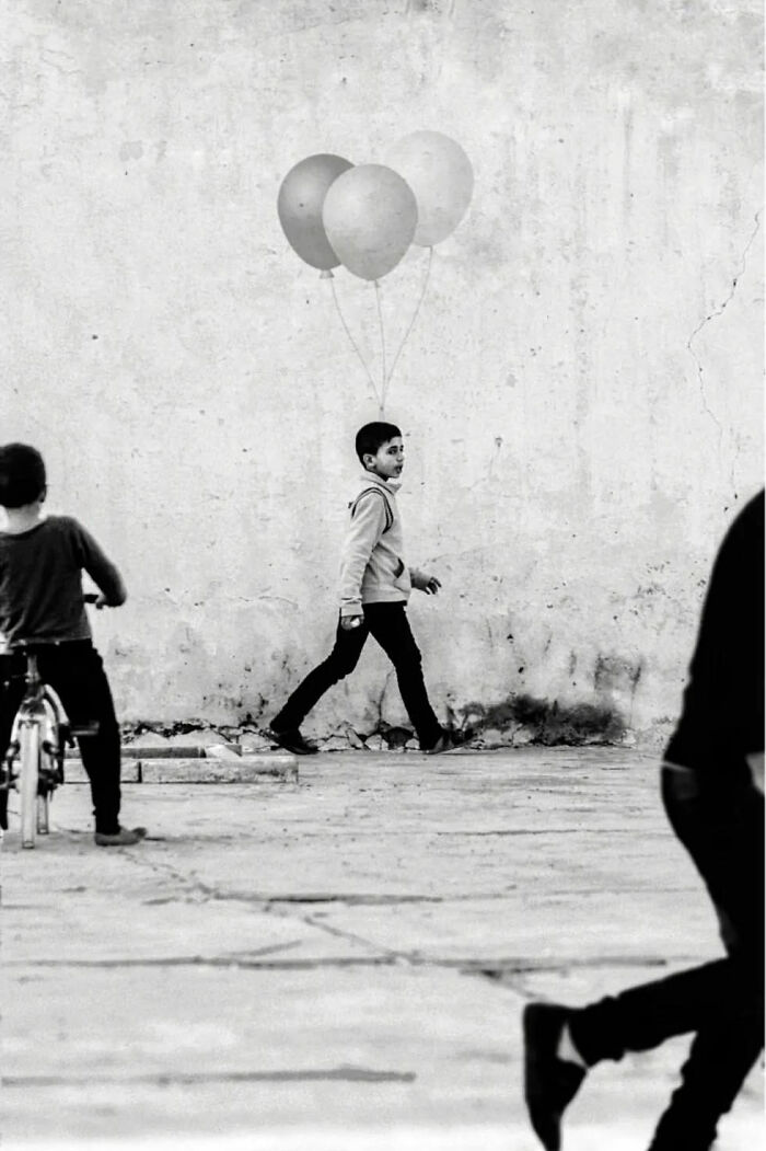 Boy walking with balloons on street, black and white street photography capturing everyday life in India.