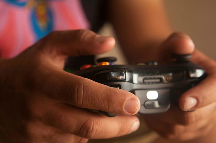 Close-up of a person holding a video game controller, illustrating over-the-top workplace rules causing frustration.