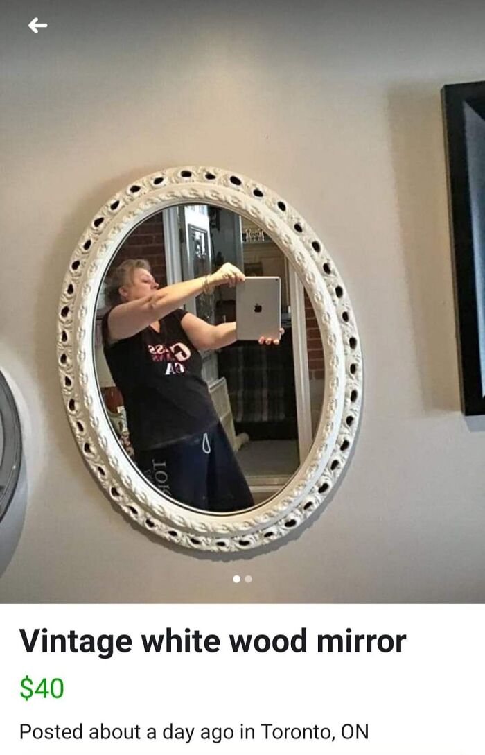 Vintage white wood mirror with ornate frame, reflection shows person taking selfie with tablet selling mirror online.