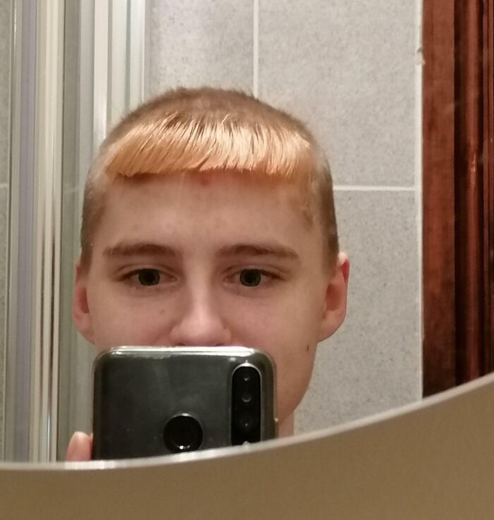 Young person with a hilariously tragic hair accident taking a mirror selfie with uneven bangs and short hair.