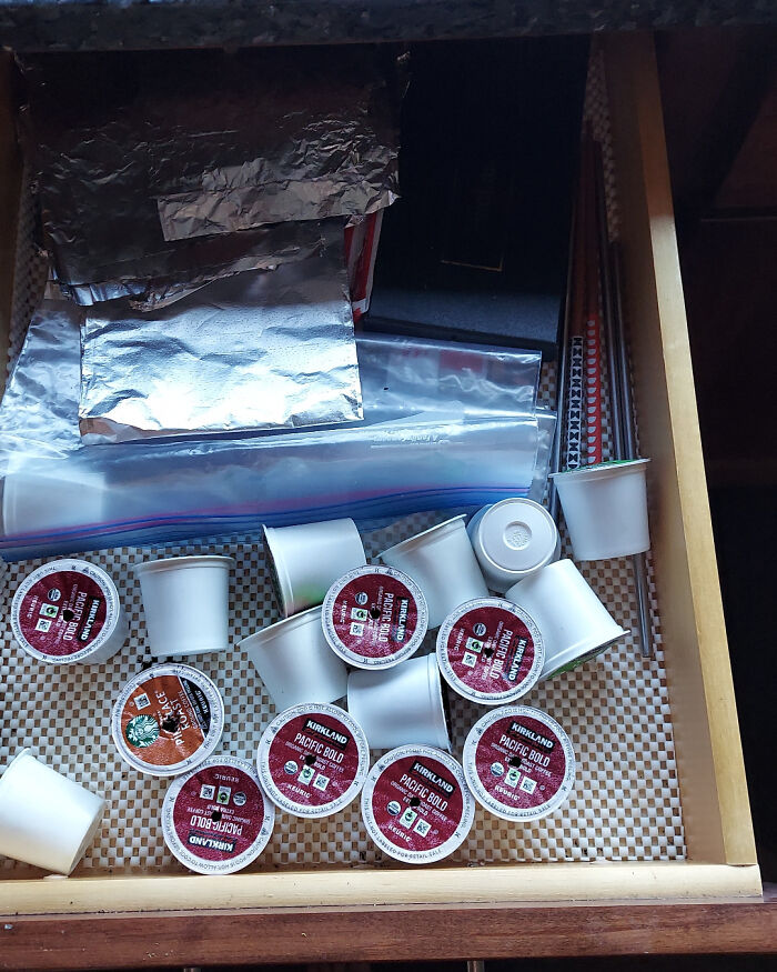 Drawer filled with scattered coffee pods and foil packets, showing infuriated family member's disorganized kitchen storage.
