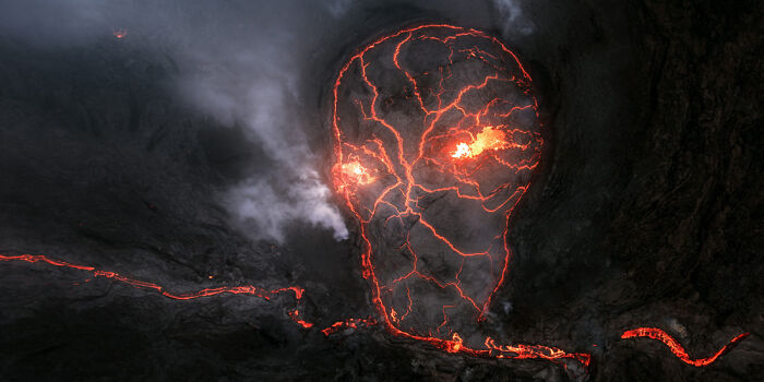 Volcanic landscape with glowing lava cracks forming a skull shape in a panoramic masterpiece from Epson Pano Awards 2025.