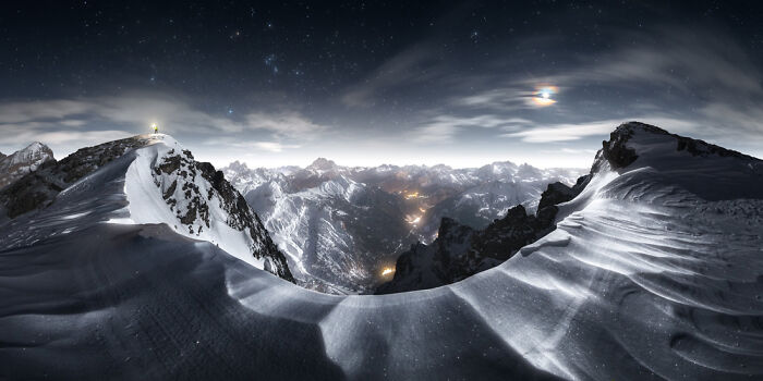 Panoramic mountain landscape at night with snow-covered peaks and starry sky showcasing panoramic masterpieces.
