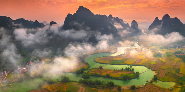 Panoramic landscape of winding river and misty mountains at sunrise, showcasing a panoramic masterpiece in natural scenery.