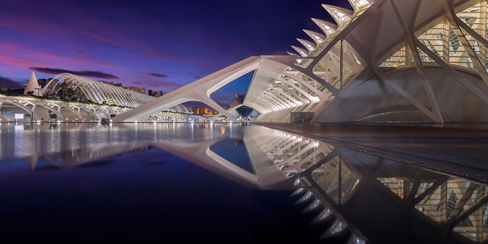 Futuristic architecture reflected in calm water during twilight, showcasing panoramic masterpieces and creative wide-angle photography.
