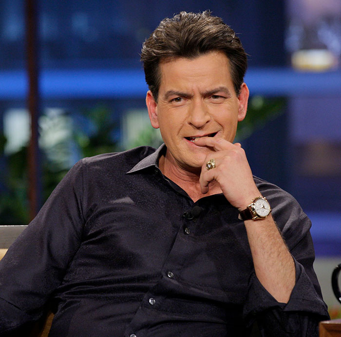 Man sitting thoughtfully, wearing a dark shirt and watch, with plastic surgeons commenting on new look trends. Man sitting thoughtfully, wearing a dark shirt and watch, with plastic surgeons commenting on new look trends.