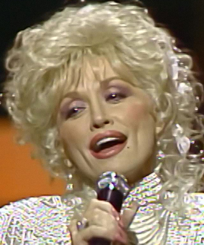 Dolly Parton performing on stage with microphone, highlighting sister raising alarm amid health struggles news. Dolly Parton performing on stage with microphone, highlighting sister raising alarm amid health struggles news.