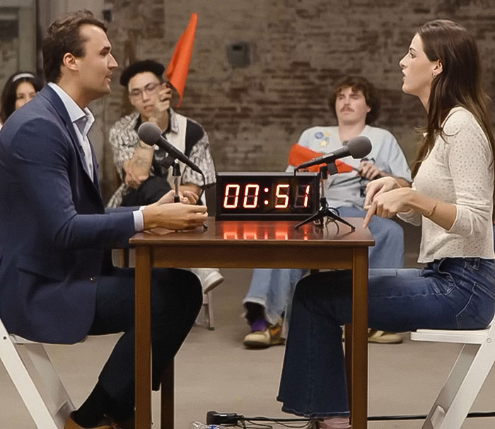 Dad discusses Life of Charlie Kirk homework assignment for 5th grader in a timed debate with a woman, audience reacts in background. Dad discusses Life of Charlie Kirk homework assignment for 5th grader in a timed debate with a woman, audience reacts in background.