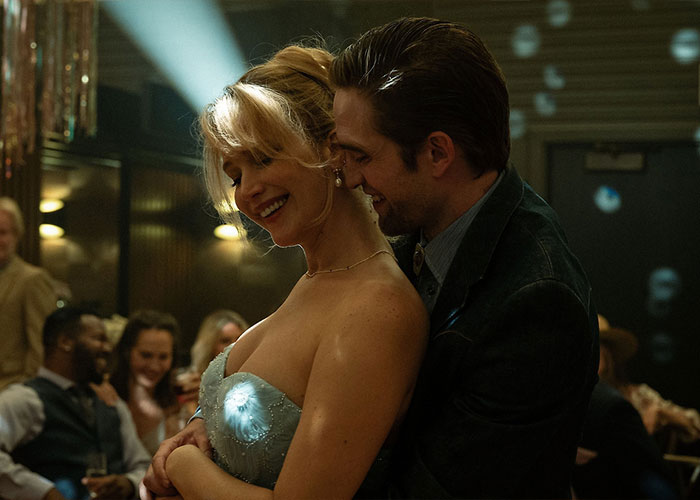 Jennifer Lawrence embraces a man in a dimly lit setting, highlighting discussions about plastic surgery plans and fan reactions. Jennifer Lawrence embraces a man in a dimly lit setting, highlighting discussions about plastic surgery plans and fan reactions.