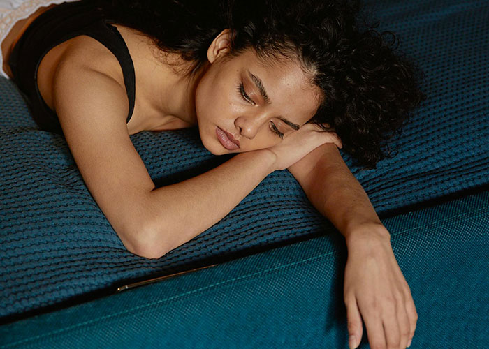 Young woman lying on a blue couch looking tired, illustrating common mental health myths debunked by psychologists.
