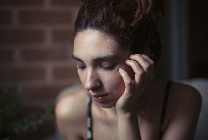 Woman sitting thoughtfully with hand on face, reflecting on marriage after husband's disturbing confession, showing emotional distress. Woman sitting thoughtfully with hand on face, reflecting on marriage after husband's disturbing confession, showing emotional distress.