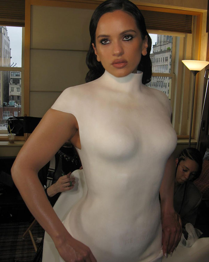 Pop star at Paris Fashion Week wearing a white body suit with bold makeup and styled hair posing indoors. Pop star at Paris Fashion Week wearing a white body suit with bold makeup and styled hair posing indoors.