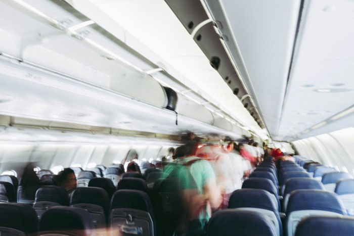 Blurred passengers moving through an airplane aisle, illustrating tension as Karen locks horns with multiple passengers on a plane. Blurred passengers moving through an airplane aisle, illustrating tension as Karen locks horns with multiple passengers on a plane.