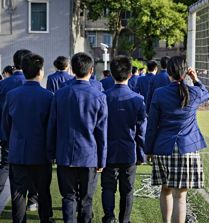 Students in blue school uniforms walking outside on a field, highlighting bullying related to clothes and support from brands. Students in blue school uniforms walking outside on a field, highlighting bullying related to clothes and support from brands.