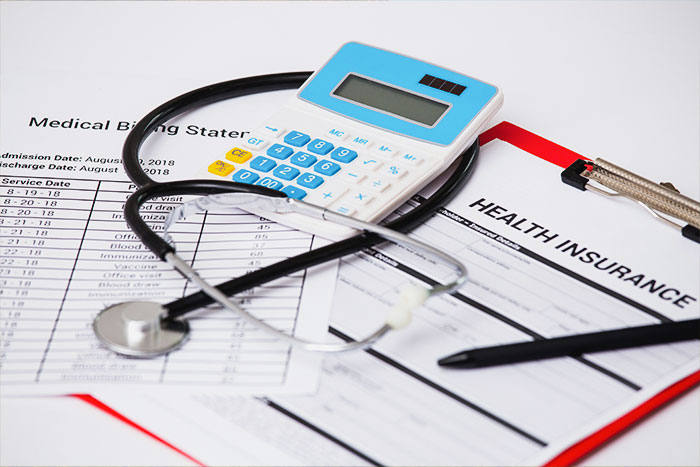 Health insurance documents with stethoscope and calculator illustrating denied coverage over key details. Health insurance documents with stethoscope and calculator illustrating denied coverage over key details.