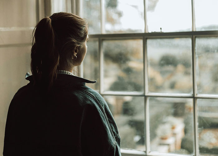 Woman with ponytail looking thoughtfully out a window, illustrating psychologists debunking mental health myths.