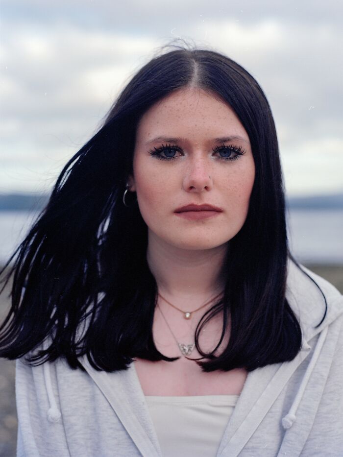 Young woman with freckles wearing a red and beige jacket, featured in award-winning photos from the 2025 Photographer of the Year contest