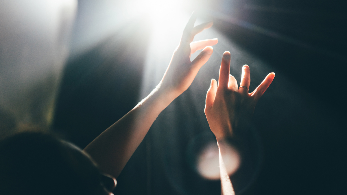 Hands reaching toward bright light with soft rays, symbolizing 999 angel number and spiritual closure mindset concepts.
