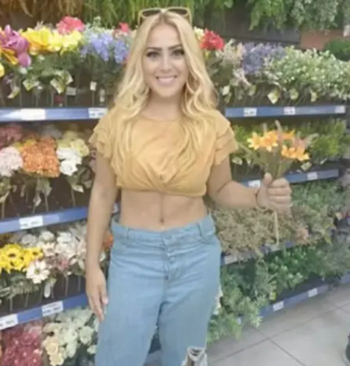 Young woman with an angel-faced appearance standing in front of flower displays holding orange flowers. Young woman with an angel-faced appearance standing in front of flower displays holding orange flowers.