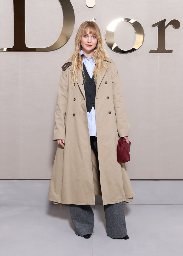 Woman in beige trench coat and gray pants posing at Paris Fashion Week 2025 celebrity looks event. Woman in beige trench coat and gray pants posing at Paris Fashion Week 2025 celebrity looks event.