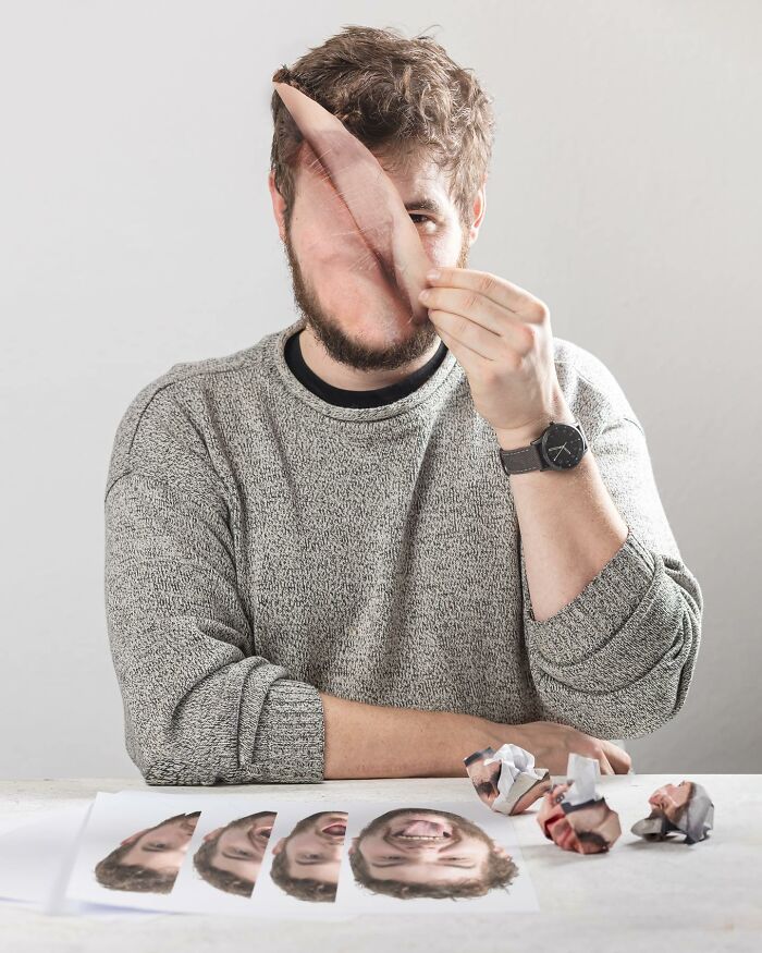 Man holding a manipulated photo of his face challenging logic with photo manipulations and printed facial images on table.