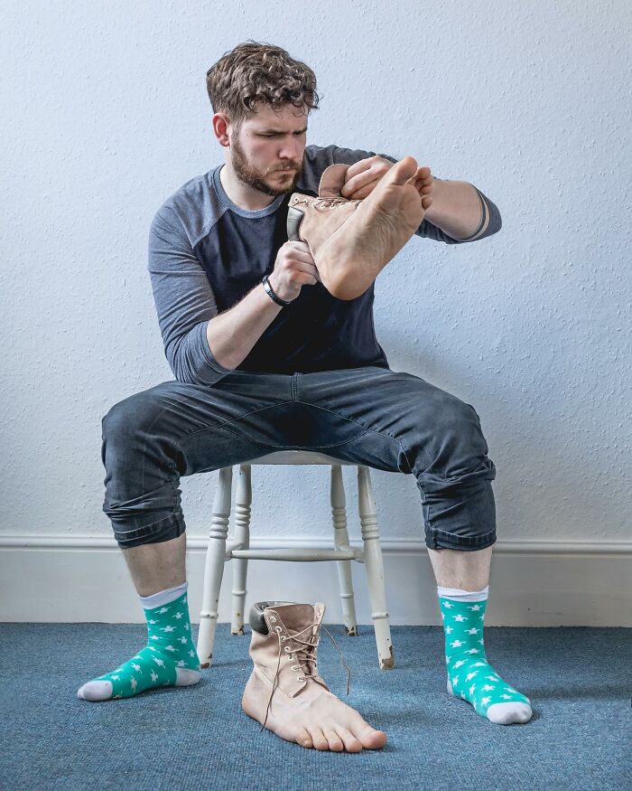 Man sitting on a chair using a boot shaped like a human foot, showcasing logic-challenging photo manipulations artwork.