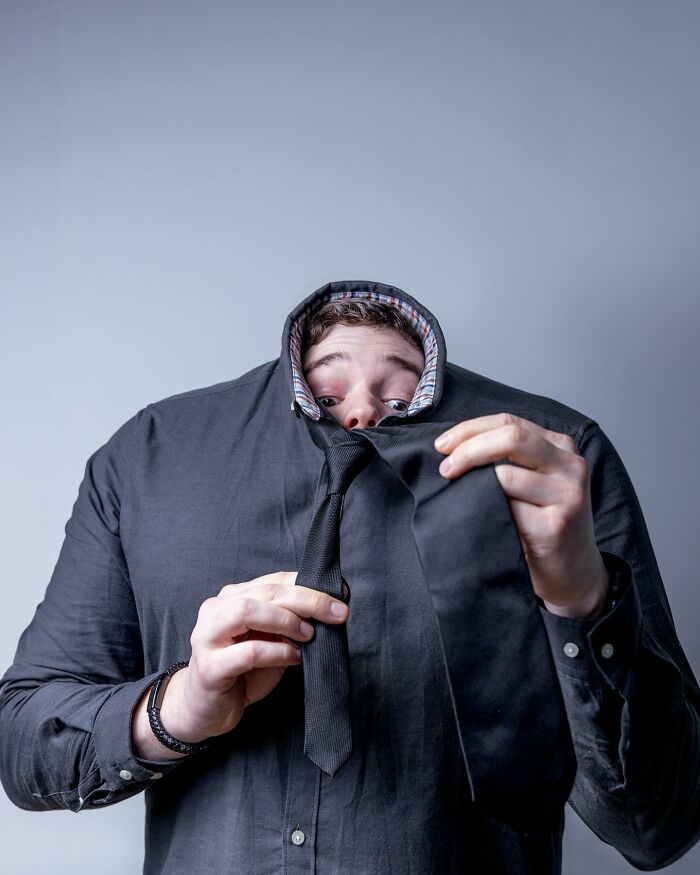 Man wearing an oversized shirt with his head peeking through an unusually high collar in a logic-challenging photo manipulation.
