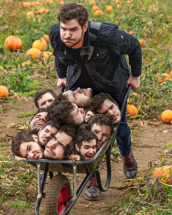 Man pushing a wheelbarrow filled with multiple edited heads of himself in a pumpkin patch, showcasing photo manipulations.