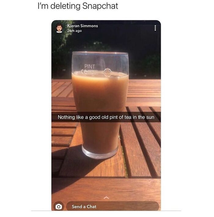 Glass of tea on a wooden table in the sun, showcasing unapologetically British humor and culture in a meme post.
