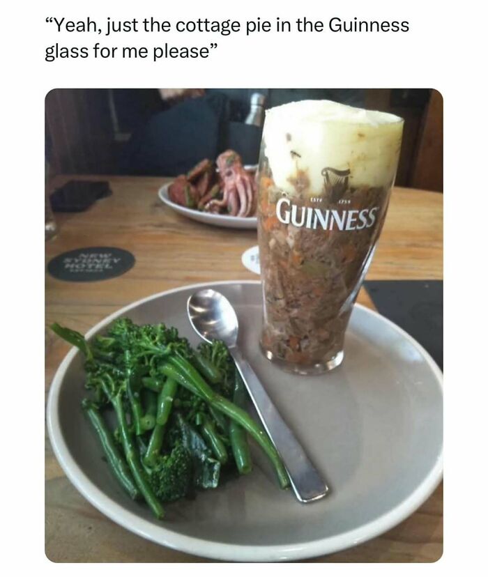 Glass of cottage pie served in a Guinness glass beside green vegetables on a plate, representing unapologetically British humor.