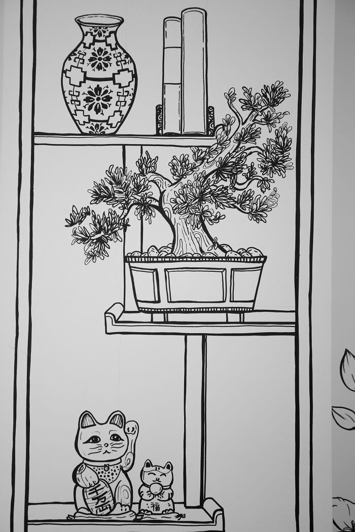 Black and white drawing inside a 2D restaurant in NYC featuring a bonsai, vase, books, and lucky cat figurines on shelves. Black and white drawing inside a 2D restaurant in NYC featuring a bonsai, vase, books, and lucky cat figurines on shelves.