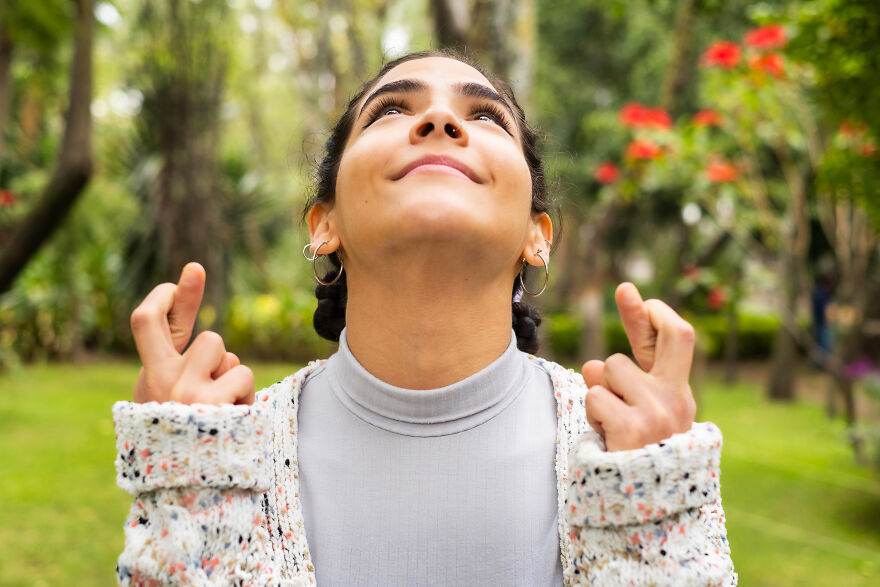 Young woman outdoors crossing fingers and looking hopeful, symbolizing belief in 999 angel number mindset. Young woman outdoors crossing fingers and looking hopeful, symbolizing belief in 999 angel number mindset.