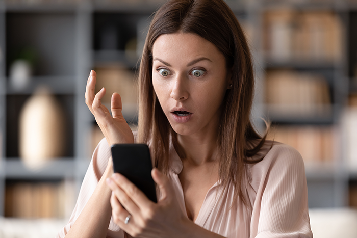 Woman surprised looking at phone, shocked by a tattoo related to her boyfriend or ex in an indoor setting. Woman surprised looking at phone, shocked by a tattoo related to her boyfriend or ex in an indoor setting.