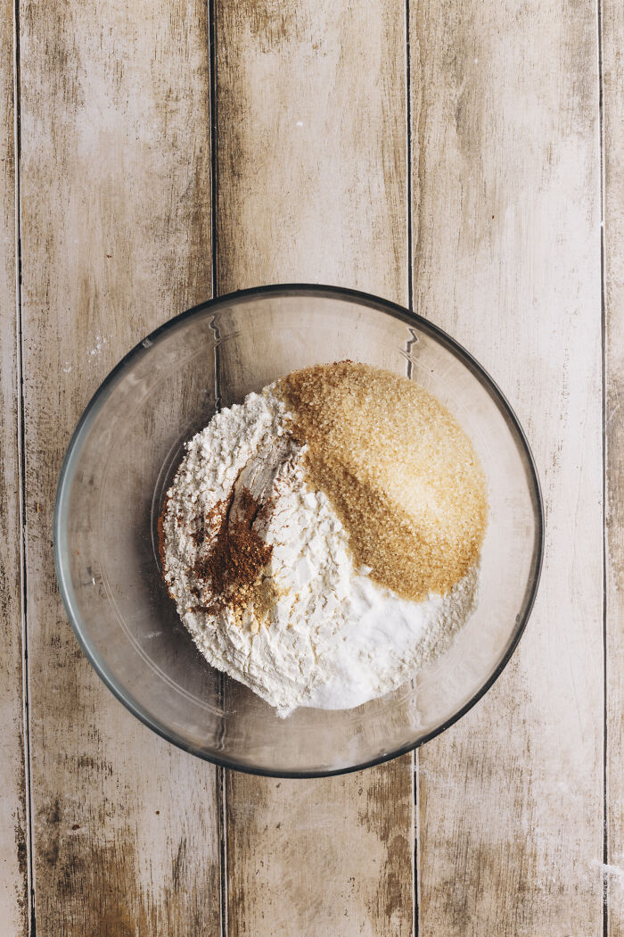 Glass bowl with flour, brown sugar, and cinnamon spices for butternut squash autumn cake recipe on wooden surface Glass bowl with flour, brown sugar, and cinnamon spices for butternut squash autumn cake recipe on wooden surface