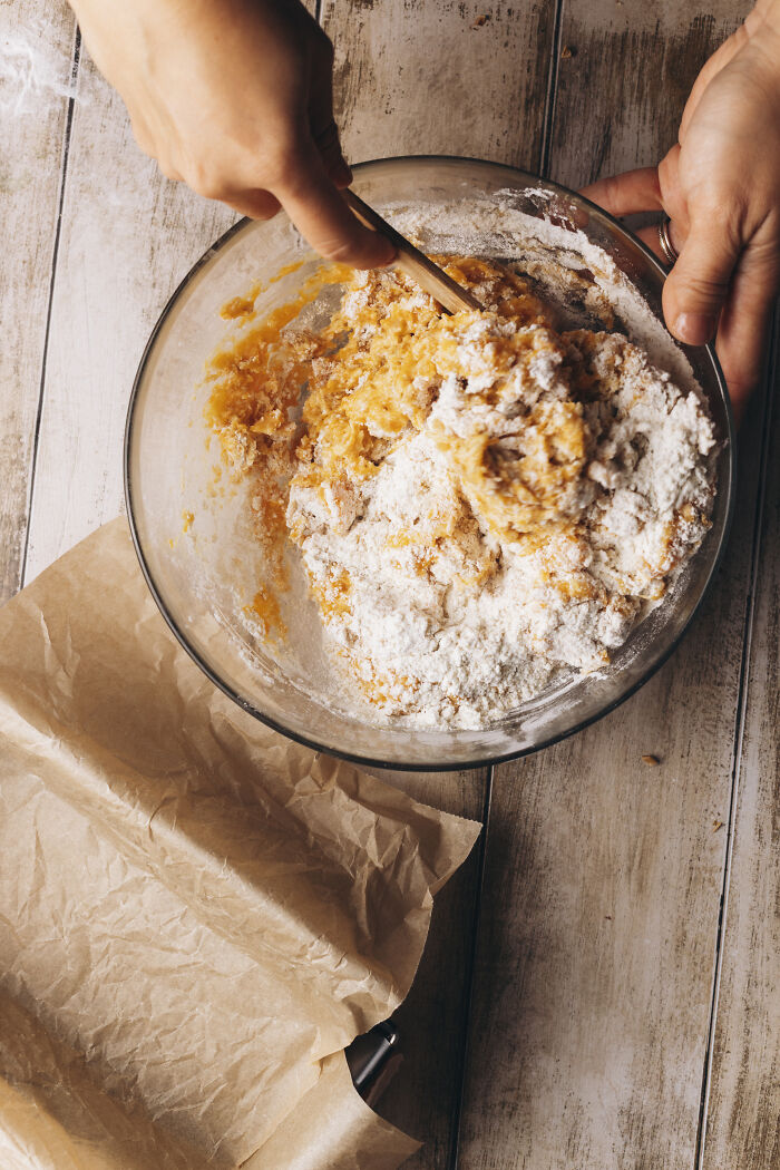 Mixing butternut squash cake batter with flour in a glass bowl on a wooden surface for an autumn recipe. Mixing butternut squash cake batter with flour in a glass bowl on a wooden surface for an autumn recipe.