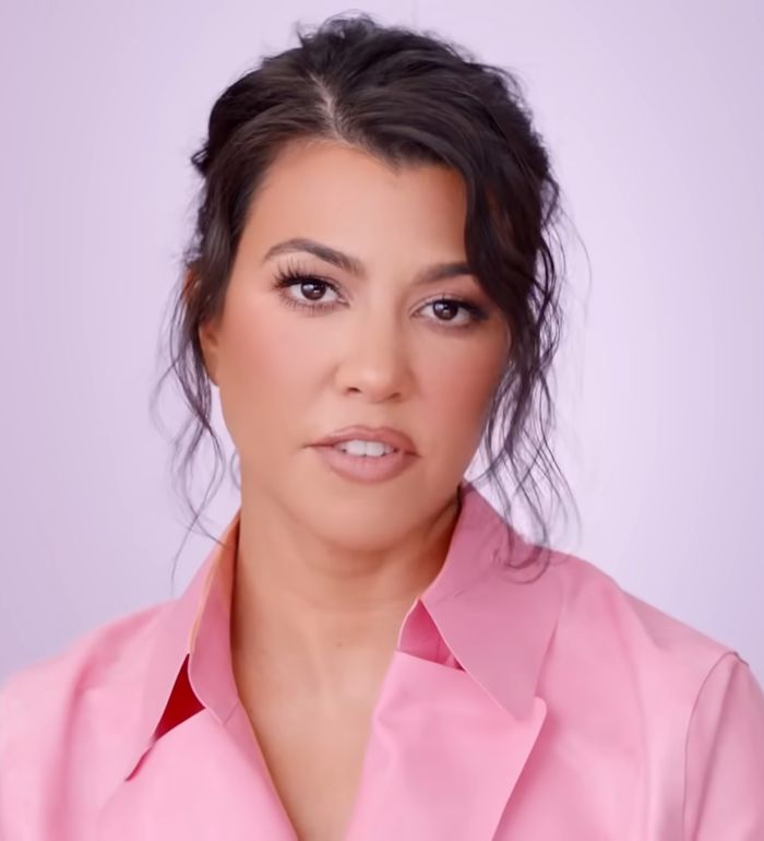 Kourtney Kardashian in a pink blouse with natural makeup, promoting lollipops for women’s private parts concept.