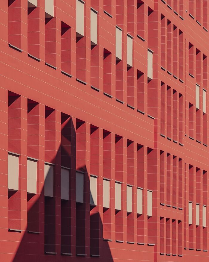 Minimalist architectural design with geometric red facade and shadow play on a modern building by Olle L.