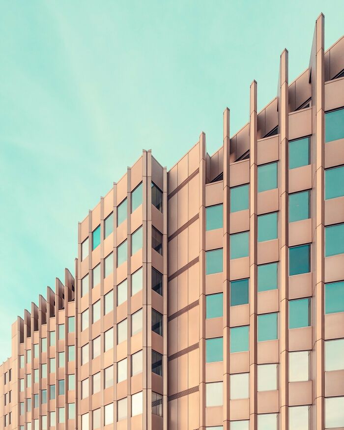 Minimalist architectural building with clean lines and large windows under a clear blue sky.