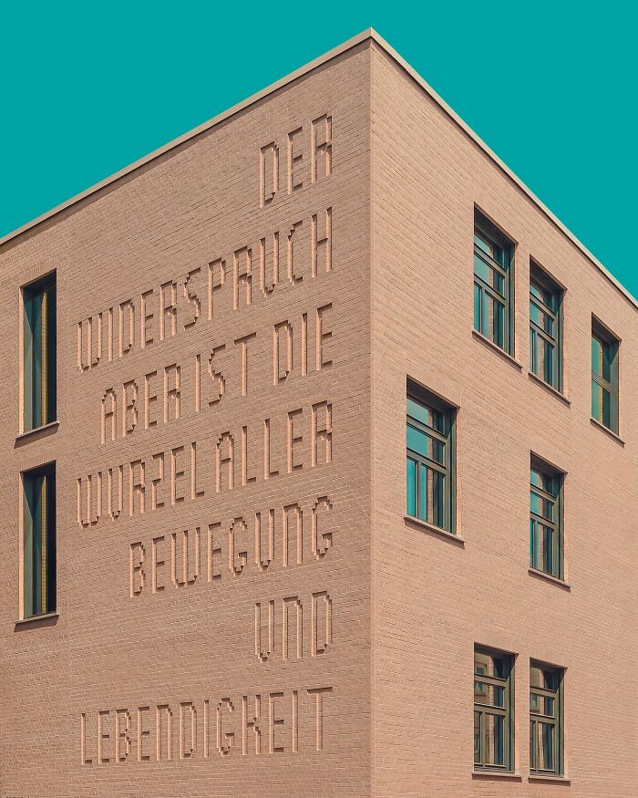 Minimalist architectural design of a brick building with clean lines and a clear structural form under a turquoise sky.