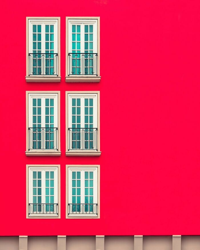 Minimalist architectural design featuring six symmetrical windows on a vibrant red building facade by Olle L.