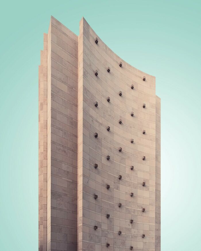 Minimalist architectural building by Olle L with smooth stone facade and geometric details against a clear blue sky.