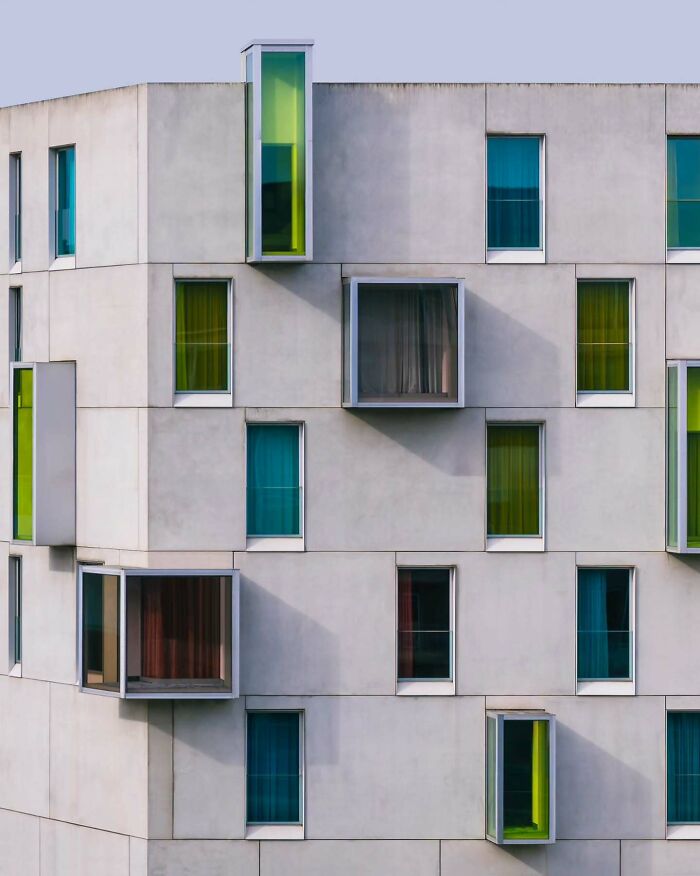 Minimalist architectural vision showcasing a modern building with colorful, protruding windows and clean concrete surfaces.