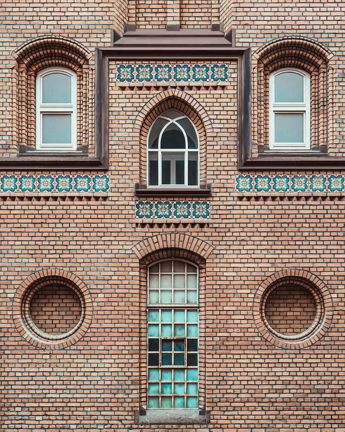 Brick building façade featuring minimalist architectural design with symmetrical windows and decorative tile accents by Olle L.
