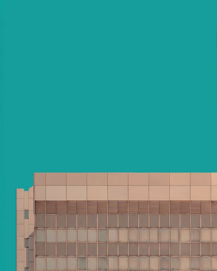 Minimalist architectural design of a modern building with clean lines and a teal sky backdrop.