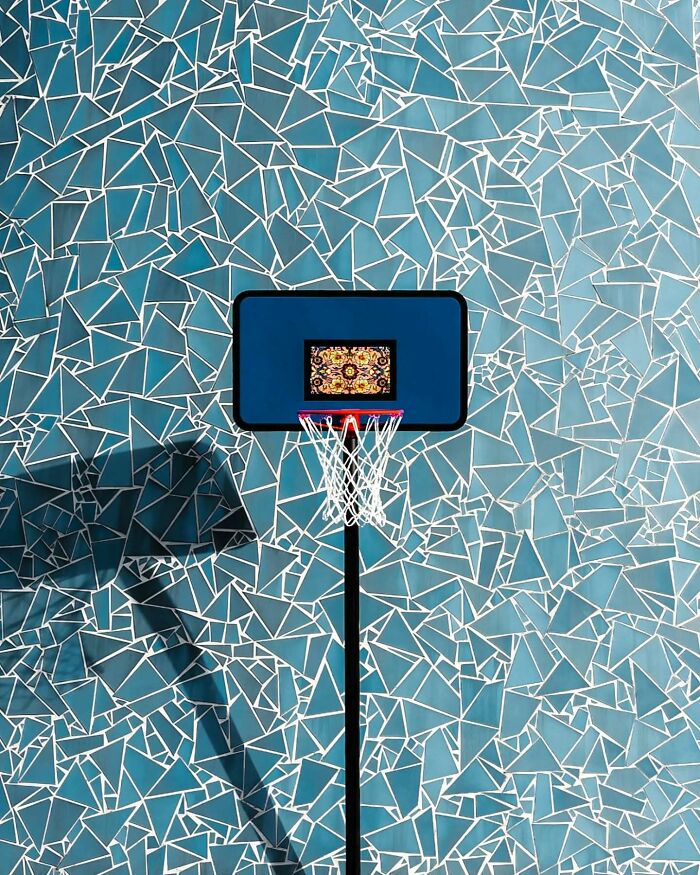 Minimalist architectural basketball hoop with geometric blue mosaic wall, showcasing modern design and artistic vision.