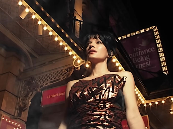 Lily Allen standing outside a theater at night, spotlighted with lights, related to brutal album about David Harbour. Lily Allen standing outside a theater at night, spotlighted with lights, related to brutal album about David Harbour.